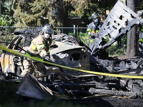 Arson investigators examine the scorched remains of a garage and the car that was inside it at 1515 Arthur Rd. on Oct. 9, 2017.