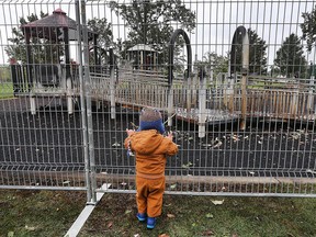 Weylin Kimble, 2, looks through safety fencing at the scorched remains of the "boundary-free" playround at Lacasse Park in Tecumseh on Oct. 11, 2017. Repair costs have been estimated at $400,000 and a 13-year-old male has been charged with arson.