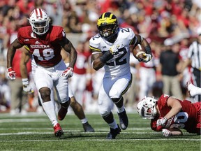 Michigan running back Karan Higdon, centre, runs between Indiana defenders Greg Gooch, left, and Chase Dutra during the first half an NCAA college football game in Bloomington, Ind., on Oct. 14, 2017.