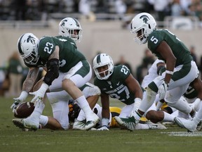 In this Sept. 30, 2017, photo, Michigan State's Chris Frey (23) recovers a fumble by Iowa's Brandon Smith, bottom rear, as Michigan State's Joe Bachie, left rear, Khari Willis (27), Andrew Dowell (5) and David Dowell, right, react during the third quarter of an NCAA college football game in East Lansing, Mich. Stopping the run has been a staple of some of Mark Dantonio's best teams at Michigan State, and there are some signs that the Spartans are returning to form in that area.