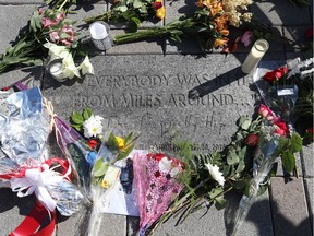 Bouquets of flowers are placed in memory of Gord Downie at the Tragically Hip commemorative plaque in Kingston, Ont. Wednesday.