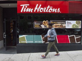 A pedestrian walk past a Tim Hortons coffee shop in downtown Toronto on June 29, 2016. The legal battle between a group of Tim Hortons franchisees and their parent company escalated today as the corporate-unsanctioned franchisee association filed a lawsuit alleging Restaurant Brands International, its subsidiary and several executives of subverting their right to associate.A lawsuit filed on behalf of two franchisees who belong to The Great White North Franchisee Association claims the defendants sought "to interfere with, restrict, penalize, or threaten franchisees from exercising their rights to associate." THE CANADIAN PRESS/Eduardo Lima.