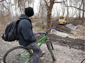 Mountain biker Jonathan Gignac watches in dismay as the unauthorized stunt course in the Little River Corridor is demolished by a bulldozer on Nov. 23, 2017.
