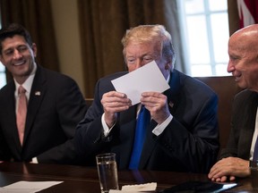 Flanked by Speaker of the House Paul Ryan and House Ways and Means Committee chairman Rep. Kevin Brady (R-TX), U.S. President Donald Trump kisses an example of what a new tax form may look like as he speaks about tax reform legislation in the Cabinet Room at the White House, Nov. 2, 2017, in Washington, D.C. Republican lawmakers unveiled their plans for a massive rewrite of the U.S. tax code.