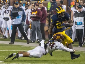 Karan Higdon of the Michigan Wolverines tries to run past the tackle of Antonio Shenault of the Minnesota Golden Gophers during a college football game at Michigan Stadium on Nov. 4, 2017 in Ann Arbor, Mich. The Wolverines defeated the Golden Gophers 33-10.
