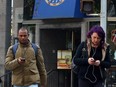 Distracted pedestrians walk across Bloor St., against a light and outside of the crosswalk, while using their cellphones in Toronto on Friday, Nov. 3, 2017.