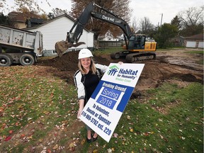 Fiona Coughlin, executive director, Habitat for Humanity Windsor-Essex, holds a sign in front of a lot on Askew Street in Leamington on Monday. In an unusual twist for Habitat, the group had to demolish an existing house to make room for a new one to be built.