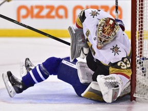 Vegas Golden Knights goalie Maxime Lagace is run over by Toronto Maple Leafs centre Zach Hyman (obscured) during the second period of an NHL game in Toronto on Nov. 6, 2017. Hyman received a penalty on the play.