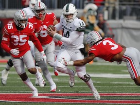 Michigan State quarterback Brian Lewerke, centre, runs the ball as Ohio State cornerback Damon Arnette, right, makes the tackle during the first half of an NCAA college football game on Nov. 11, 2017, in Columbus, Ohio.