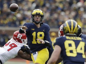 FILE - In this Oct. 28, 2017, file photo, Michigan quarterback Brandon Peters (18) throws while pressured by Rutgers linebacker Brandon Russell (49) during the second half of an NCAA college football game in Ann Arbor, Mich. Peters' play has helped Michigan win three straight games, scoring 35 in each. No. 5 Wisconsin will face its sternest test yet this season when No. 19 Michigan visits Camp Randall Stadium in the home season finale.