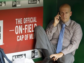 This Sept. 4, 2015, photo shows Atlanta Braves assistant general manager and director of pro scouting John Coppolella talking on the phone in the dugout during batting practice before a baseball game against the Washington Nationals at Nationals Park, in Washington. Baseball Commissioner Rob Manfred has hit the Atlanta Braves with heavy sanctions, including the loss of nine players, for rules violations committed by the team in the international player market. Manfred on Nov. 21, 2017, also placed former Braves general manager Coppolella on the permanently ineligible list. Former Braves special assistant Gordon Blakeley, the team's international scouting chief, is suspended from performing services for any team for one year.