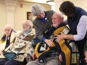 'Quilted hug.' Second World War veteran Alan Brownlie gets a warm gift from Quilts of Valour area representative Janet Bergeron, left, and quilter Pauline Gaudette during a ceremony honouring six veterans at the Royal Marquis retirement residence, Nov. 18, 2017.