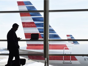 FILE - In this Jan. 25, 2016, file photo, a passenger talks on the phone as an American Airlines jets sit parked at their gates at Washington's Ronald Reagan National Airport.