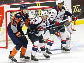 The Windsor Spitfires Matthew MacDougall and Cole Purboo, right, battle Flint Firebirds defence Fedor Gordeev, left, for position in front of Flint goalie Luke Cavallin.