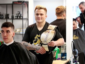 MMA fighter T.J. Laramie, centre, poses with his TKO Canadian championship belt at Padrone Barber Shop, Dec. 15, 2017.  Customer Quentin Broad, left, waits for his haircut to continue as Laramie displays his impressive belt. Aaron Nguyen and barber Carlos Moukhayber are shown at right.