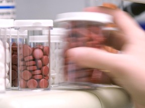 A person takes medication from a shelf.