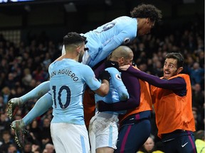 Manchester City's players and substitutes celebrate with Manchester City's Spanish midfielder David Silva (C) after he scores their second goal during the English Premier League football match between Manchester City and West Ham United at the Etihad Stadium in Manchester, north west England, on December 3, 2017. Manchester City won the game 2-1.