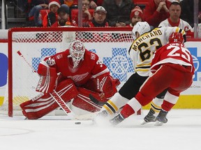 Boston Bruins left wing Brad Marchand (63) scores against Detroit Red Wings goalie Jimmy Howard (35) during overtime of an NHL hockey game, Dec. 13, 2017, in Detroit. Boston won 3-2.
