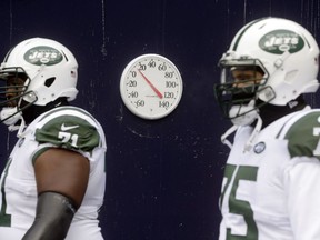 A thermometer in the runway displays a temperature in the teens as New York Jets tackle Ben Ijalana (71) and defensive end Xavier Cooper (75) take the field for an NFL football game against the New England Patriots, Sunday, Dec. 31, 2017, in Foxborough, Mass.