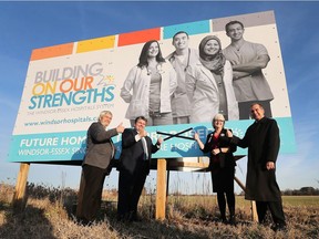 In this Dec. 1, 2017, file photo, Essex County Warden Tom Bain, left, Windsor Regional Hospital president and CEO David Musyj, Hotel-Dieu Grace Health president and CEO Janice Kaffer and co-chair of the steering committee Dave Cooke pose on the proposed site for the new mega-hospital will be built. They marked an X over the word "proposed" on the sign which sits at the corner of County Road 42 and Concession 9.