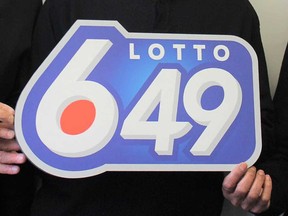 Prize winners hold up a Lotto 6/49 logo in this 2017 file photo.