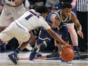 Detroit's Jermaine Jackson Jr. (1) and Michigan's Zavier Simpson chase a loose ball during the first half of an NCAA college basketball game, Dec. 16, 2017, in Detroit.