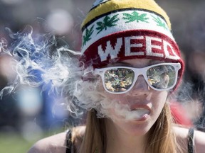 A woman exhales while smoking a joint during the annual 420 marijuana rally on Parliament Hill on April 20, 2016 in Ottawa.