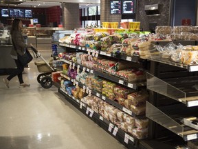 Various brands of bread sit on shelves in a grocery store.