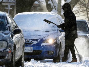 A motorist begins the task of clearing snow off a vehicle in downtown Windsor on the morning of Dec. 12, 2017.