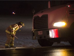 A firefighter examines a transport truck involved in a fatal collision with a pedestrian on County Road 46 in Tecumseh on the night of Dec. 11, 2017.