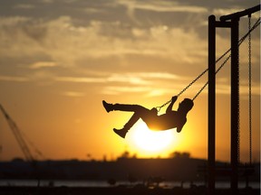 Li Xirui, 13, visiting from China, is pushed on the swing by his mother at McKee Park as the sun sets next to him on Thursday, June 8, 2017.