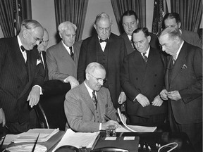 In this April 3, 1948 file photo, U.S. President Harry Truman signs the history-making foreign aid bill into law at White House ceremony in Washington. Looking onare: Sen. Arthur Vandenberg (R-Mich), left; Secretary of Treasury John W. Snyder; Rep. Charles A. Eaton (R-NJ); Sen. Tom Connally (D-Tex); Secretary of Interior Julius Krug; House Speaker Joseph W. Martin (R-Mass); and Rep. Sol Bloom (D-NY).    Partly hidden in right background is Secretary of Agriculture Clinton Anderson.
