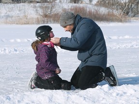 Claire Dunnell, 7, gets her helmet adjusted by her father Mike Dunnell on frozen Blue Heron Pond in Windsor's east end.