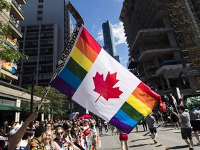 A man holds a flag on a hockey stick during the Pride parade in Toronto on June 25, 2017.
