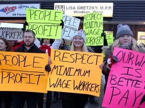 Patrick Clark, left, Jocelyn Gates, and Alex Forbes, right, participate in a rally organized by UWindsor New Democrats to support fairer wages and protection for workers in front of the office of MPP Lisa Gretzky, Friday Jan. 12, 2018.