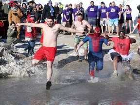 Alex Ilie, left, Brad Spencer, Aaron Gallant and Roman Jackson, all of Team Maiysn's Caped Canucks, enter the bone-chilling water of Lake Erie during the 18th annual Polar Bear Dip supporting Childcan and Access County Community Support Services at Kingsville's Cedar Beach, Jan. 13, 2018.