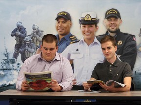Jacob Lucier, left, and brother Noah have both enrolled in the first co-op program of its kind for the Royal Canadian Navy. The brothers are triplets — their sister did not sign up — and they are shown here with a recruitment photo at HMSC Hunter in Windsor.