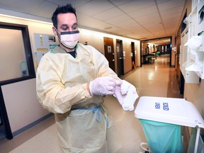 Mike Drouillard, a registered nurse at the Windsor Regional Hospital Ouellette campus puts on personal protective equipment Monday, Jan. 8, 2018, to guard against the influenza virus while interacting with a patient.