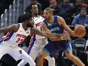 Detroit Pistons forward Reggie Bullock (25) fouls Charlotte Hornets guard Nicolas Batum (5) as Pistons guard Ish Smith, center, helps defend the basket during the first half of an NBA basketball game Jan. 15, 2018, in Detroit.