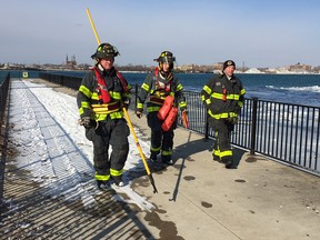 Firefighters walk away from the Detroit River after a 53-year-old man was pulled from the water on Jan. 31, 2017. One more person was believed to still be missing, but the search was called off in the evening.