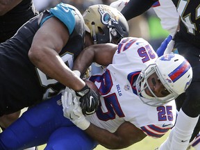 Jacksonville Jaguars defensive end Calais Campbell, top, stops Buffalo Bills running back LeSean McCoy (25) after short gain in the first half of an NFL wild-card playoff football game, Sunday, Jan. 7, 2018, in Jacksonville, Fla.