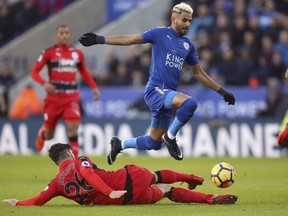 Leicester City's Riyad Mahrez, right, and Huddersfield Town's Christopher Schindler battle for the ball during their English Premier League soccer match at the King Power Stadium in Leicester, England, Monday Jan. 1, 2018.