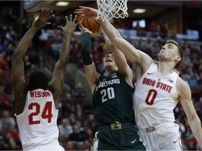 Michigan State guard Matt McQuaid, center, goes up to shoot between Ohio State forward Andre Wesson, left, and center Micah Potter during the first half of an NCAA college basketball game in Columbus, Ohio, Sunday, Jan. 7, 2018.