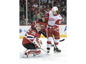 New Jersey Devils goaltender Cory Schneider (35) deflects the puck as Detroit Red Wings left wing Tyler Bertuzzi (59) looks for a rebound during the first period of an NHL hockey game Monday, Jan. 22, 2018, in Newark, N.J.