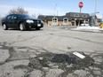 Potholes litter city roads in this file photo.   A motorist manoeuvres around a large pothole at the intersection of Windermere Road and Tecumseh Road. East.