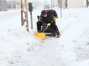From the seat of his mobility scooter, Don Hamel clears snow from the Erie Street East sidewalk on Feb. 9, 2018.