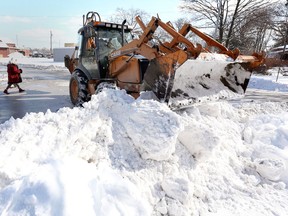 Backhoe operator Brad Smith moves mounds of snow on Monmouth Road blocking access to the sidewalk on Feb. 12, 2018.