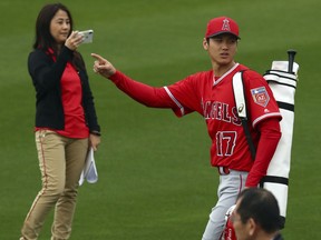 Los Angeles Angels' Shohei Ohtani gestures to fans as he takes the field during a spring training baseball practice on Wednesday, Feb. 14, 2018, in Tempe, Ariz.