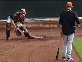 San Francisco Giants manager Bruce Bochy, right, watches catcher Buster Posey during a spring training baseball practice on Feb. 15, 2018 in Scottsdale, Ariz.