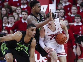 Wisconsin's Ethan Happ, right, bumps up against Michigan State's Nick Ward, center, and Miles Bridges, left, during the first half of an NCAA college basketball game Sunday, Feb. 25, 2018, in Madison, Wis.